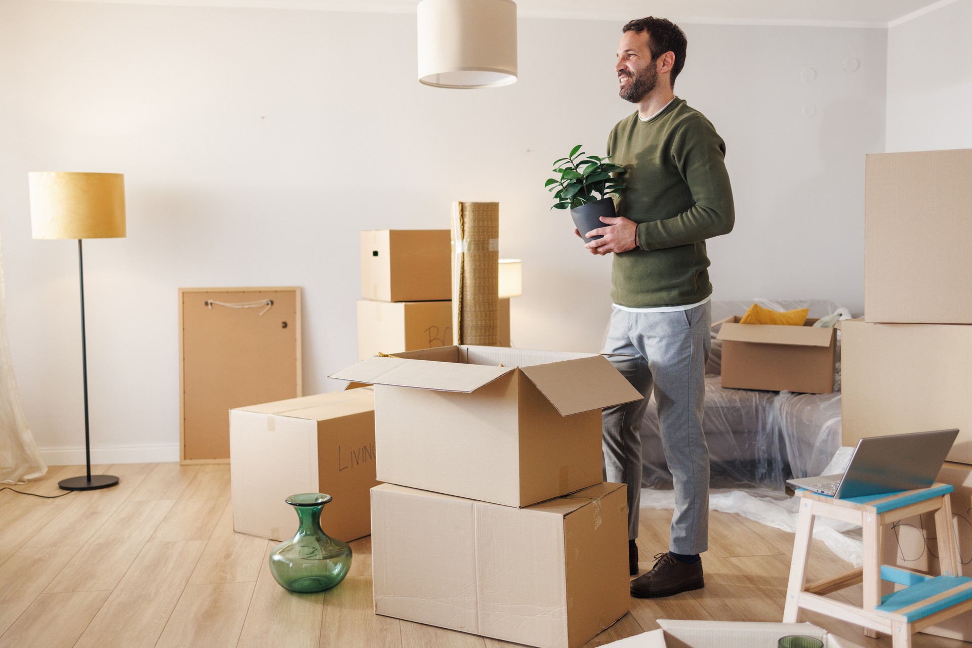 A man holding a potted plant in his new home